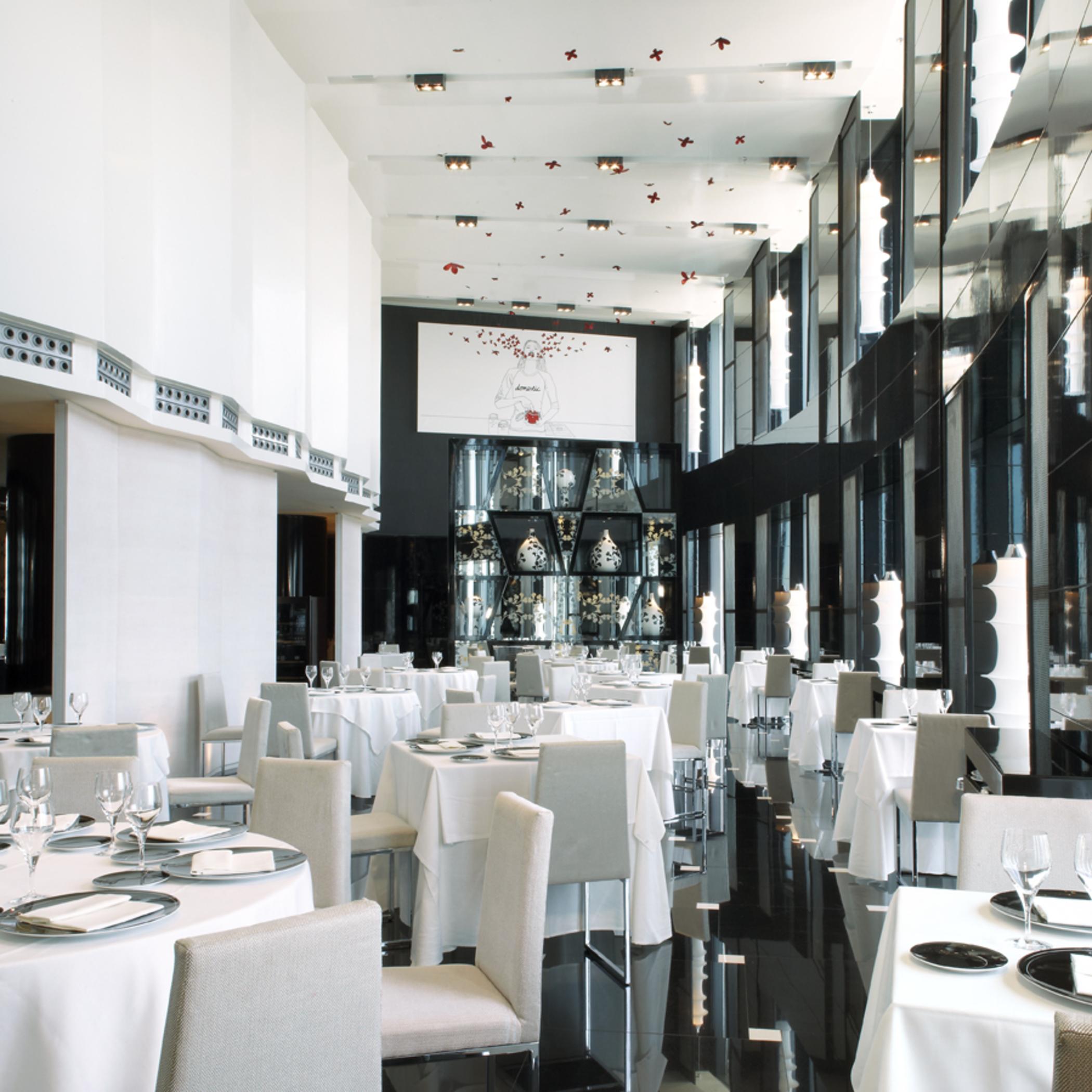 Eurostars Madrid Tower Hotel Exterior photo The photo shows a modern and elegant restaurant interior. The space features tables covered with white tablecloths, arranged neatly with plates and glassware. The decor includes large glass windows that allow natural light to fill the room, and the w