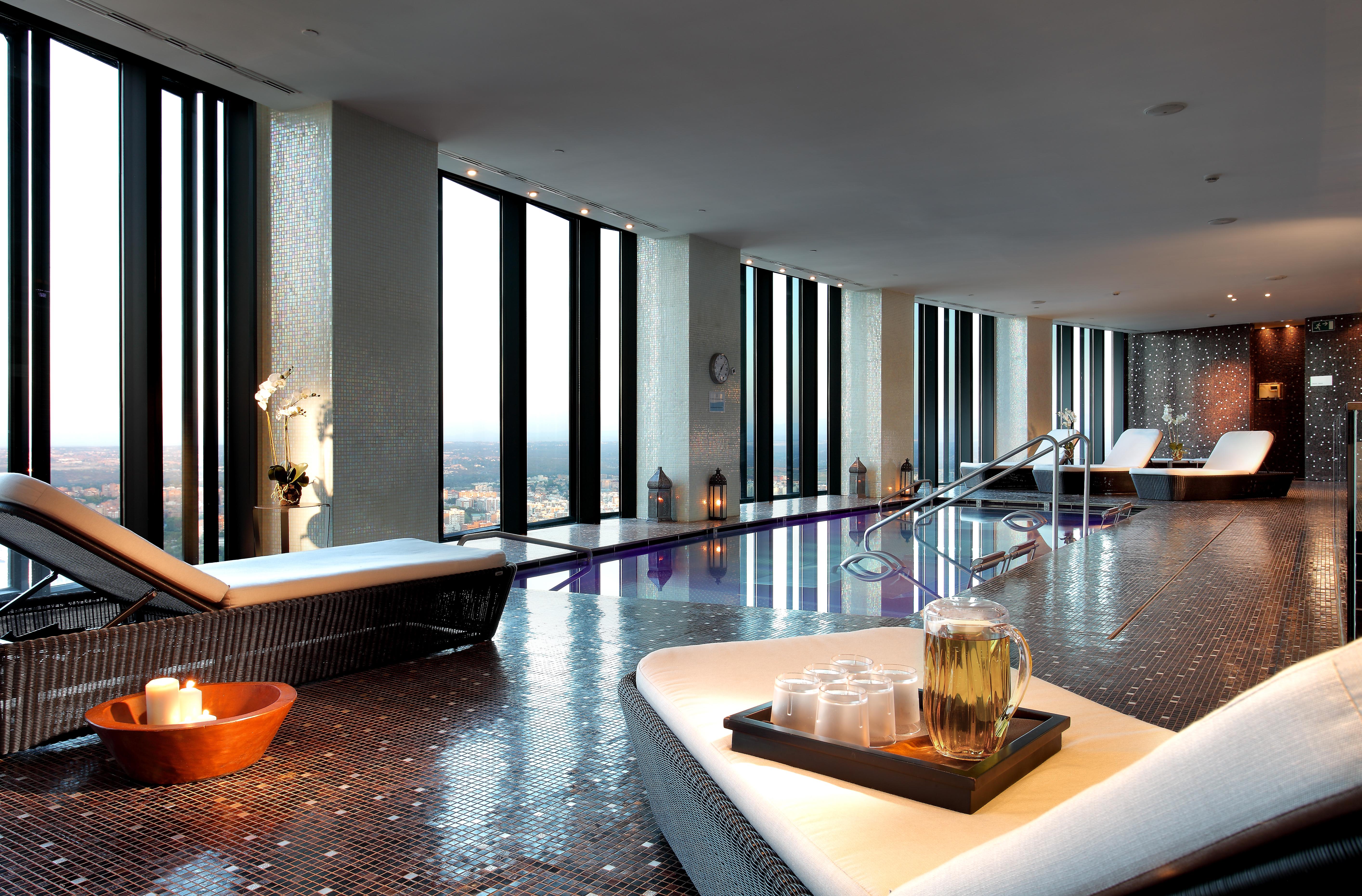 Eurostars Madrid Tower Hotel Exterior photo The photo depicts a luxurious spa interior with large windows that offer a panoramic view of the outside. The space features sleek, modern lounge chairs and a tranquil atmosphere. There is a pool area, and the floor is tiled with reflective materials