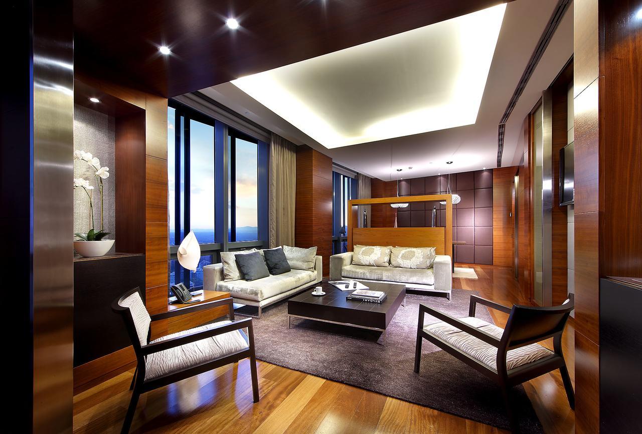 Eurostars Madrid Tower Hotel Exterior photo The photo depicts a modern and elegantly designed living room. The space features large windows that allow natural light to flood in, showcasing a beautiful view outside. The flooring is polished wood, and the color palette incorporates warm tones, i