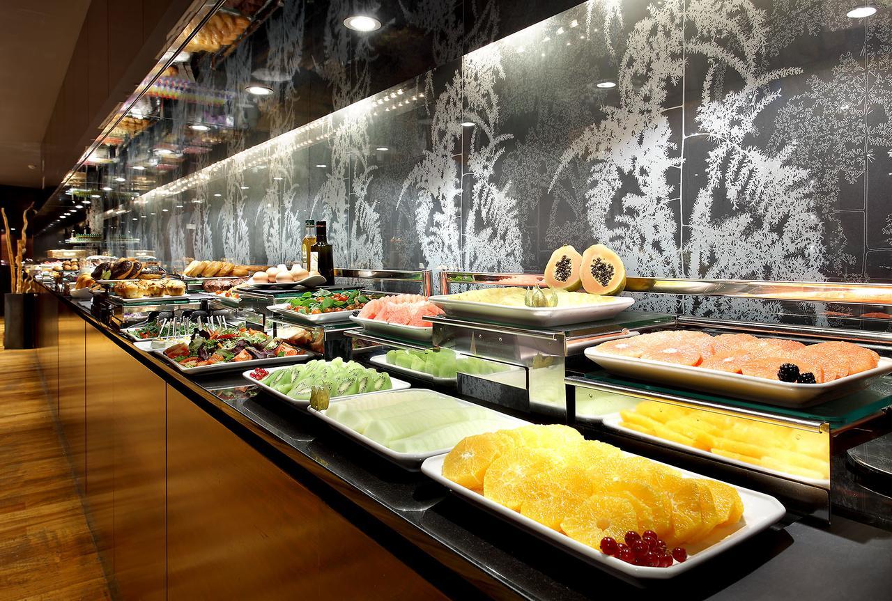 Eurostars Madrid Tower Hotel Exterior photo The photo shows a buffet display featuring a variety of dishes and ingredients. There are plates filled with different types of food, including seafood, fruits, and vegetables. The arrangement is visually appealing, with the food presented on glass s