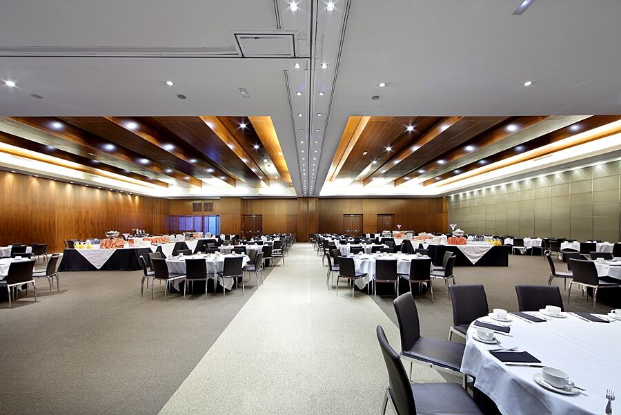 Eurostars Madrid Tower Hotel Exterior photo The photo depicts a spacious banquet hall or conference room. It features a series of tables arranged in a grid pattern, covered with white tablecloths and adorned with black tablecloths at the edges. Each table is set with plates, cutlery, and glass